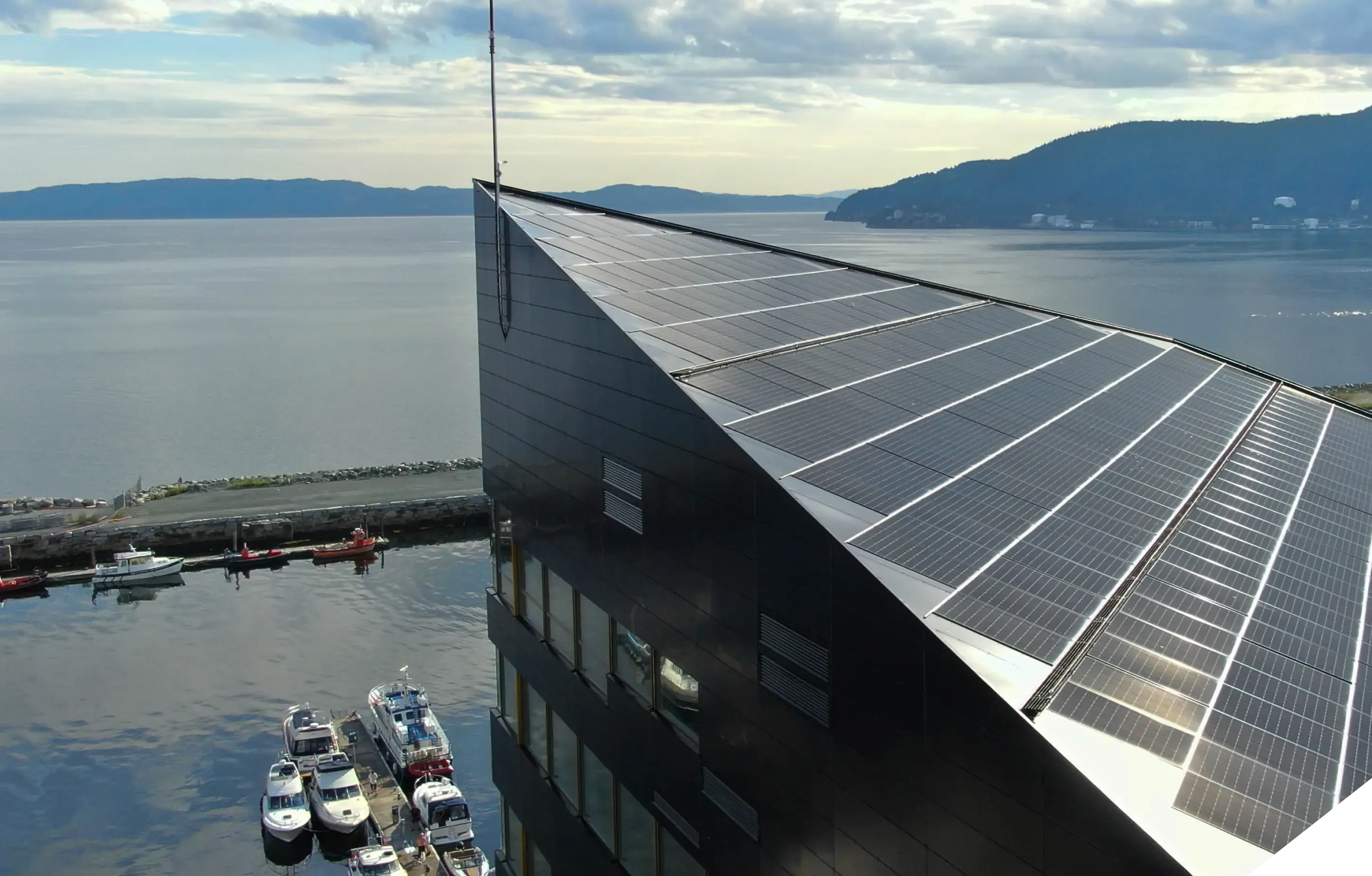 Commercial building with a solar-clad roof beside the fjord