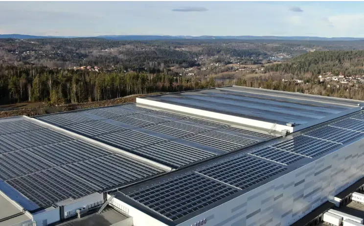 Flyfoto av et bygg med solcellepaneler på flatt tak