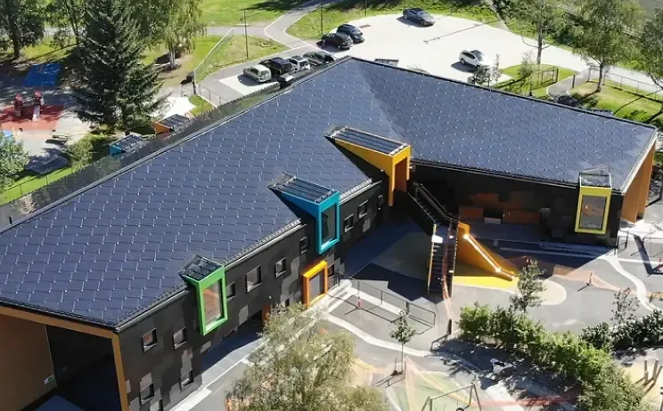 Flyfoto av en skole med lekeplass og solceller integrert i taket